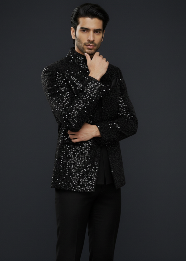 Man wearing a black sequin jacket against a dark background